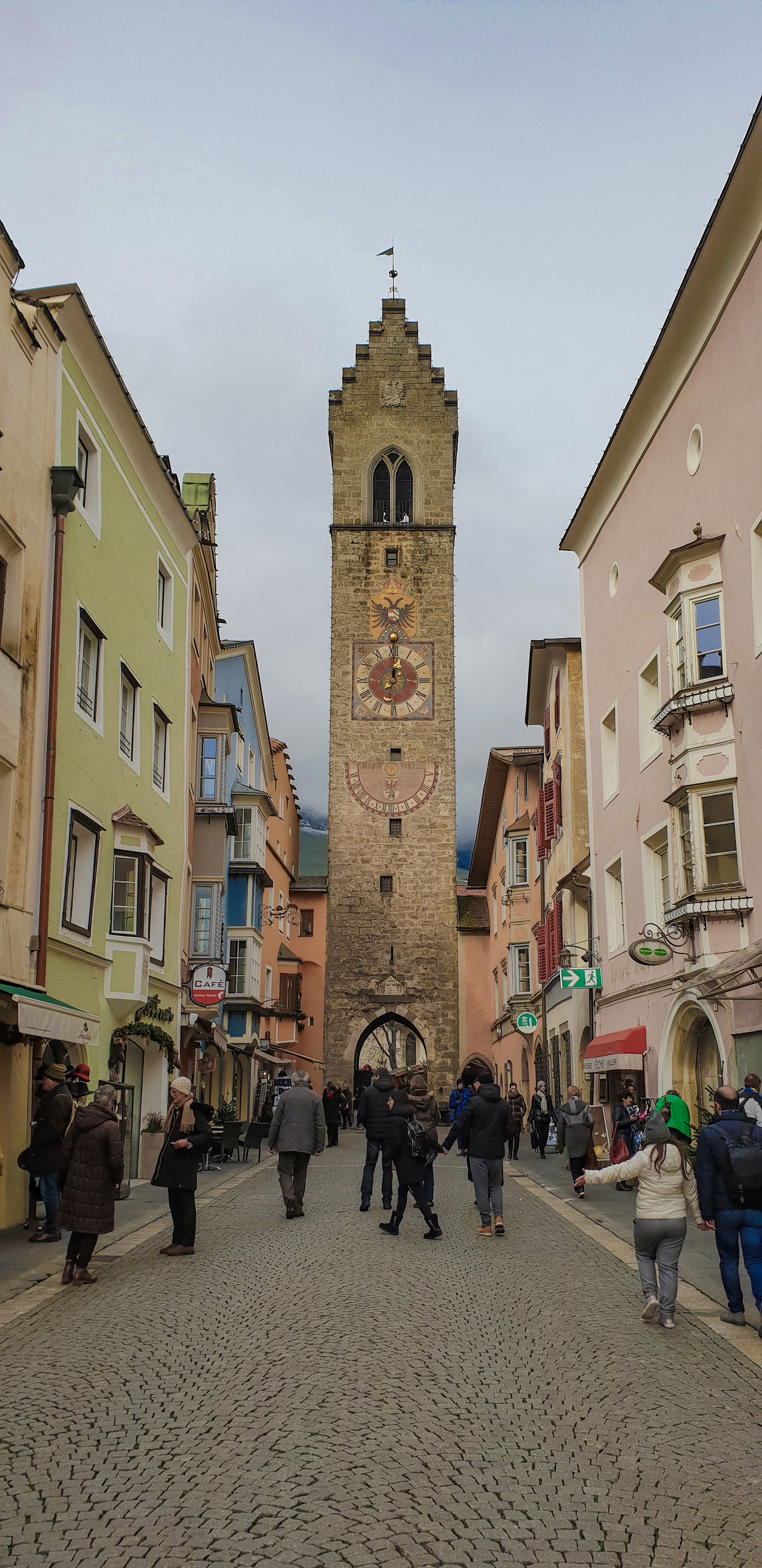 Stone facade of the Torre delle Dodici in Vipiteno, with its round clock and lower semicircular dial